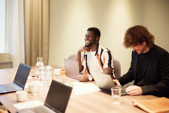 Diverse business partners discussing while sitting in meeting room at office