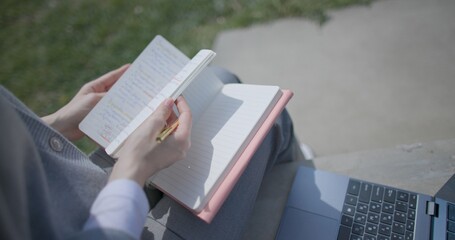 A close-up shot of a hand-held girl holding a pen and leafing through a notebook with handwritten notes. © Anatoly Repin