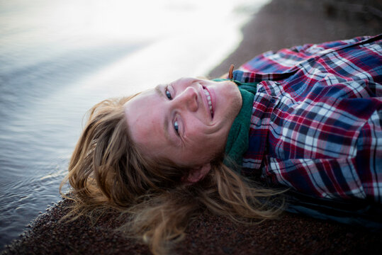 Portrait of smiling man lying down by shore at beach