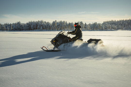 Shot of person riding snowmobile on open snowy plain