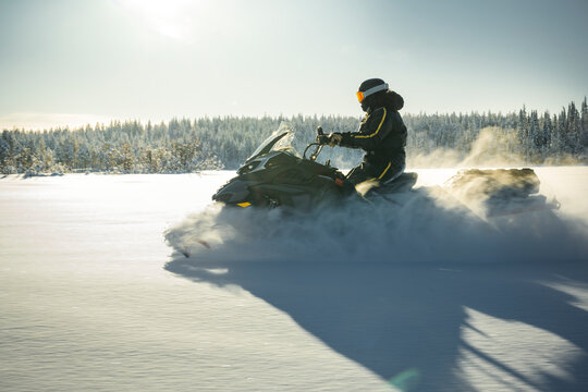 Shot of person driving snowmobile through snowy landscape