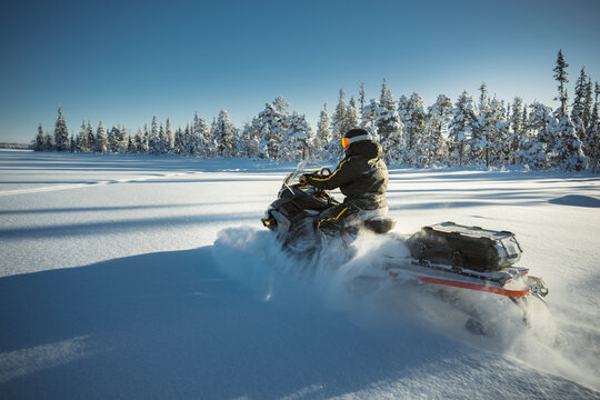 Shot of rider driving snowmobile through winter forest
