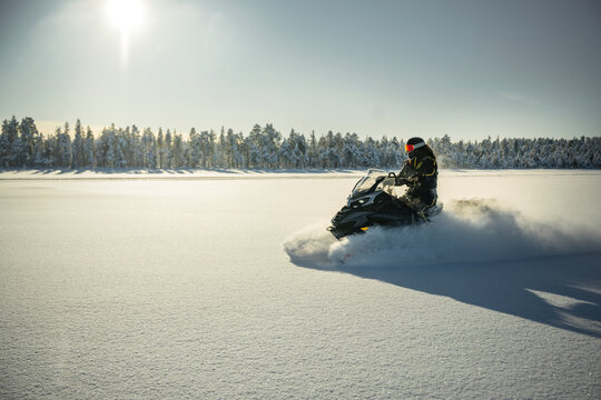 Shot of person driving snowmobile through snowy landscape