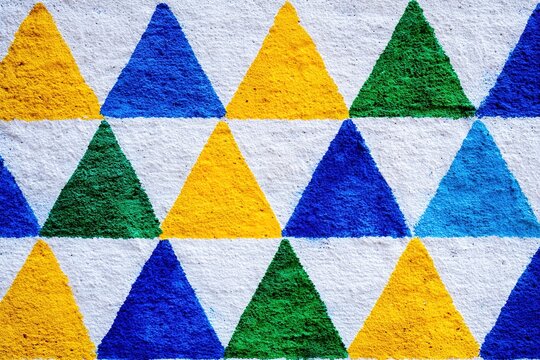 Geometric street art mural with vibrant green yellow and blue triangles on textured wall