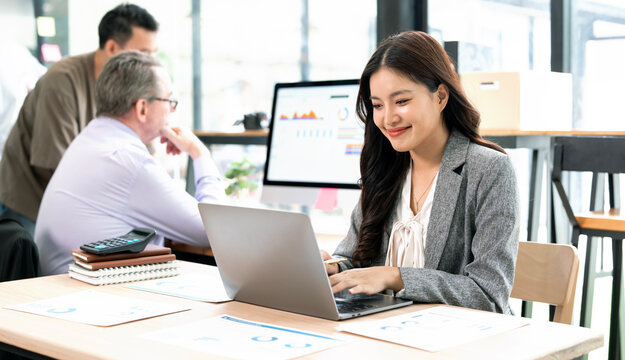 Happy Asian Businesswoman Smiling While Working on Laptop