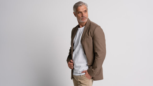 Serious middle-aged man posing in front of a grey background with copy space.