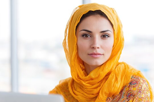 Young woman in yellow hijab and floral pattern scarf portrait indoors with soft natural light