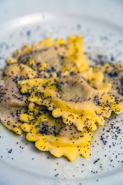 Close-up shot of homemade Italian ravioli sprinkled with black poppy seeds on white plate