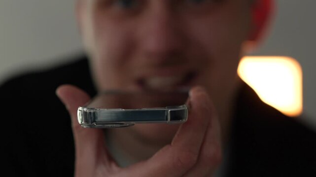 A close-up of a man recording a voice message on a mobile phone