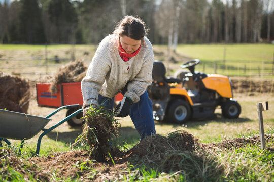 Woman pulling weeds from garden bed while working in farm