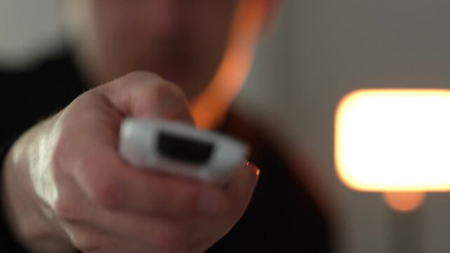 An air conditioner remote control in the hands of a person adjusting the temperature in a room