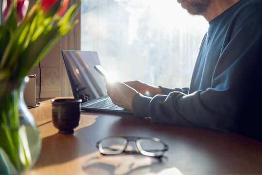 Businessman working on phone and laptop at home office