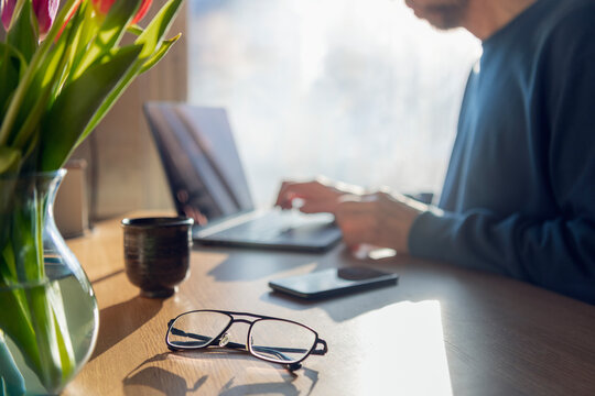 Eyeglasses on table with with businessman working in background