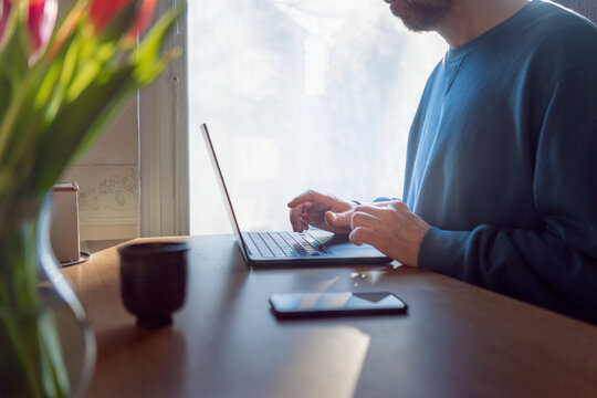 Midsection of businessman working on laptop while sitting at desk in home