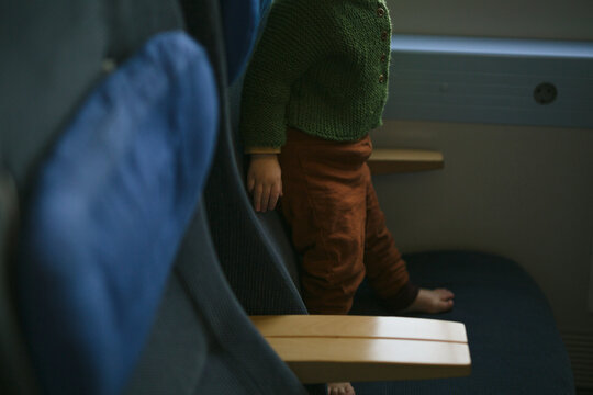 Low section of toddler baby standing on seat in train