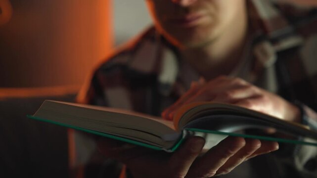A man reads a book and turns over the paper pages.
Interesting literature and detective stories in a homely evening atmosphere.