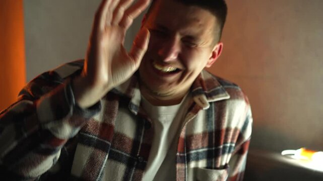 A young man in a plaid shirt smiles and shyly waves his arms.
A hearty laugh at a very funny joke.