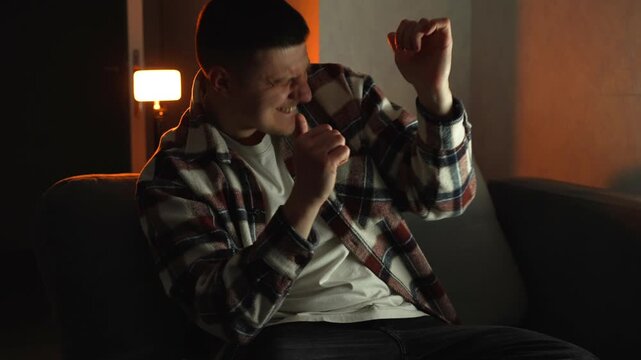 A cheerful man in a small room is rejoicing and dancing.
Showing happy emotions, having fun, and smiling.