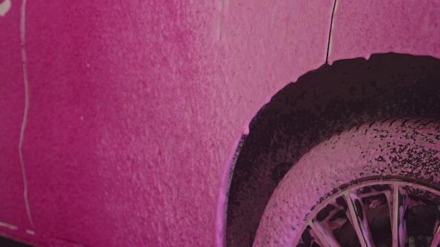 Closeup Wheel Arch Soaked In Pink Foam With Visible Tread And Rim, Textured Suds Clinging To Fender And Panel