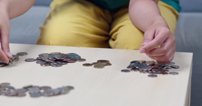 A person meticulously sorting and counting coins a table highlighting financial management.