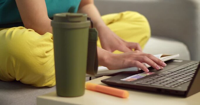 A focused individual types a laptop in a cozy home environment surrounded by personal items.