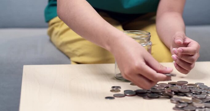 A child learns importance of saving money by collecting coins in a jar fostering financial habits.