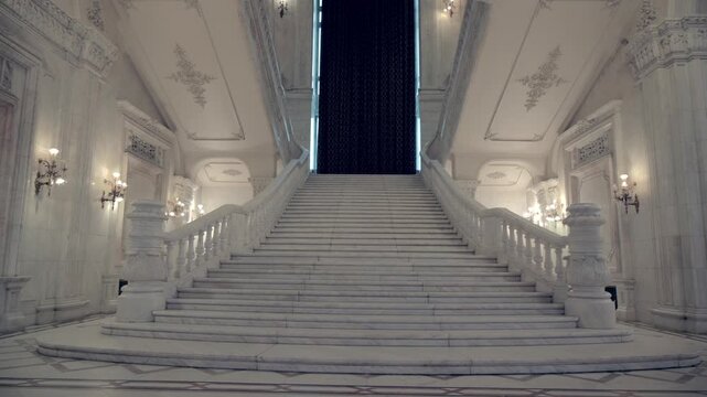 Grand marble staircase inside Palace of Parliament in Bucharest Romania with neoclassical architecture and ornate columns.