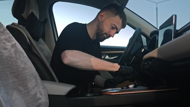 Caucasian Man Cleaning Center Console Inside Car, Wearing Gloves, Organizing Compartment, Wiping Leather