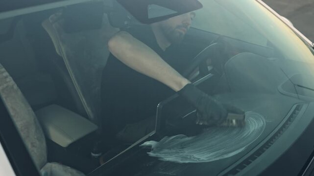 Car interior detailing, a man cleaning the car interior with a special brush and chemicals