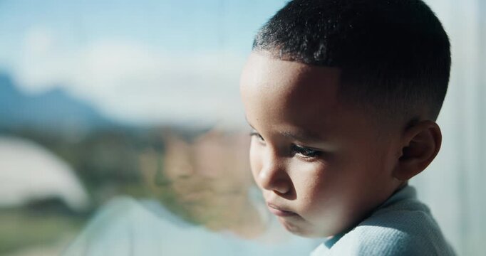 Sad, boy and thinking with window for trauma, mental health or anxiety on glass in home. Thoughtful, kid or child with depression, reflection or regret for lonely fear, crisis or bullying in house