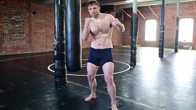 White man training in MMA gym average guy training fight sport, vertical image. showing of his physique 