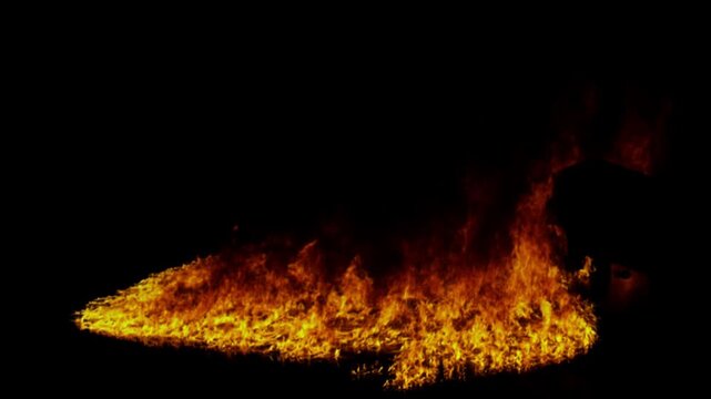 Realistic ground fire burning with intense orange flames and sparks isolated on a black background for compositing.