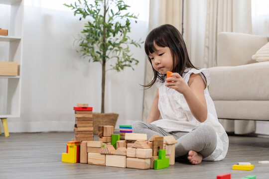Happy children play and learn, education, homeschool little girl create wooden toy block build the house, improving intelligence and knowledge with mother, supporting emotional quotient creativity