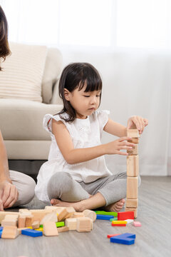 Happy children play and learn, education, homeschool little girl create wooden toy block build the house, improving intelligence and knowledge with mother, supporting emotional quotient creativity