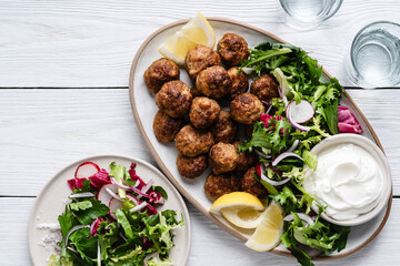 Meatballs served green salad and yogurt based dip on tray, comfort food © istetiana