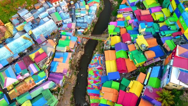 Aerial view of Kampung Warna Warni Jodipan featuring vibrant multi-colored rooftops along a river bank in Kecamatan Blimbing, Jawa Timur, Indonesia.