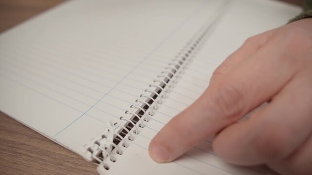 hand tearing a page out of a spiral notebook, selective focus.
