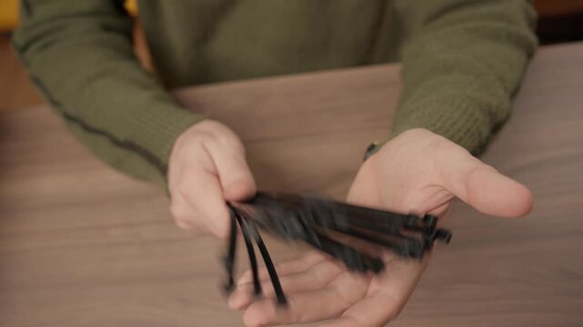 Man holding a bundle of black plastic cable ties in his open hand.