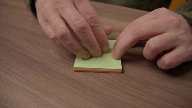 Person lifting a memo note from a multi-colored stack of post-it papers, office and organization concept.
