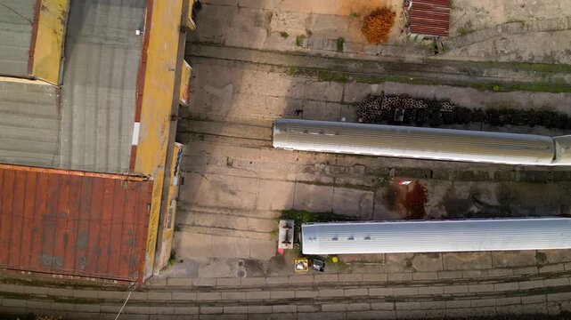 Aerial view of a railway maintenance depot with several passenger train carriages parked on parallel tracks beside a large workshop building, showing rail infrastructure, rolling stock and servicing f