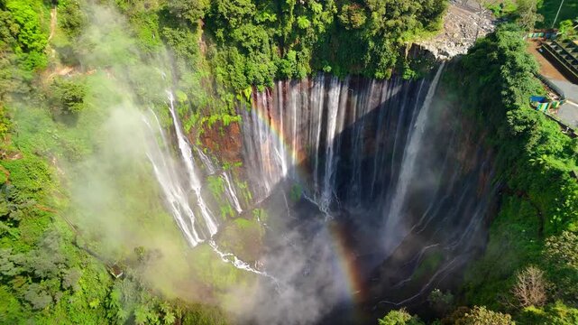 Aerial view of Tumpak Sewu Waterfall with multiple cascades falling into a misty canyon surrounded by lush tropical forest Kecamatan Pronojiwo, Jawa Timur, Indonesia.