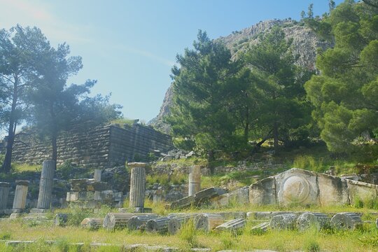 Wide landscape panorama of the ancient Greek ruins of the Temple of Athena in Priene archaeological site, Aydin, Turkey. Scattered marble Ionian columns, intricate reliefs, and architectural fragments