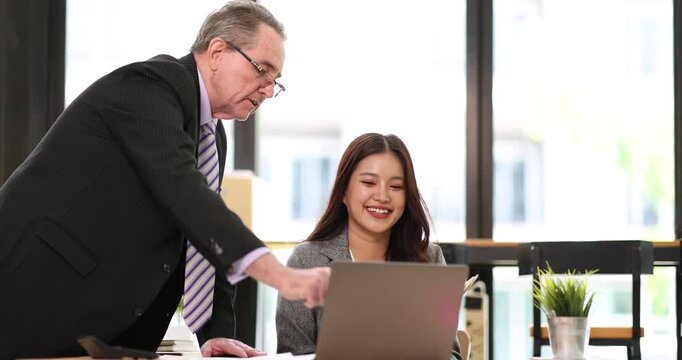 Diverse business colleagues reviewing documents and discussing project details in a modern office setup, fostering teamwork and professional development