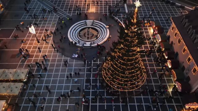 Aerial view of Christmas festive market in Brasov square at dusk with illuminated tree and historic buildings architecture.
