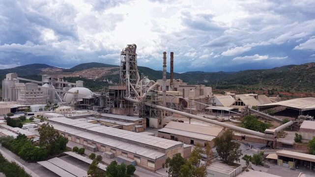 Aerial view of a large cement plant featuring a multi-stage cyclone preheater tower, spherical clinker storage dome, rotary kiln, vertical silos and conveyor systems