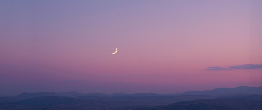 A wide-angle scene showcasing a crescent moon above a pastel violet horizon