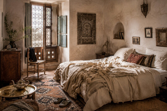  Dormitorio acogedor de estilo r&uacute;stico con cama deshecha, textiles suaves, muebles de madera y luz natural que entra por una gran ventana.
