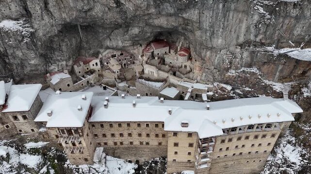 4K aerial drone view of Sumela Monastery under snow in winter season, historic Greek Orthodox monastery carved into a cliff in Trabzon, Turkey