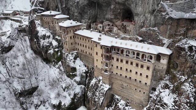 4K aerial drone view of Sumela Monastery under snow in winter season, historic Greek Orthodox monastery carved into a cliff in Trabzon, Turkey