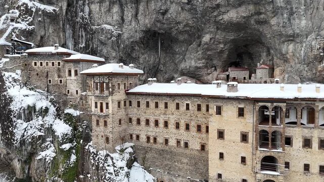 4K aerial drone view of Sumela Monastery under snow in winter season, historic Greek Orthodox monastery carved into a cliff in Trabzon, Turkey